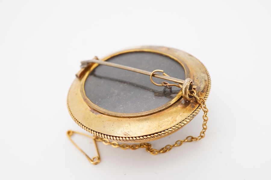 A garnet brooch, second half 19th century, designed in the Archaeological Revival style, centring on a large foiled cabochon garnet measuring approximately 25 x 21mm, within a border applied with rope twist decoration an